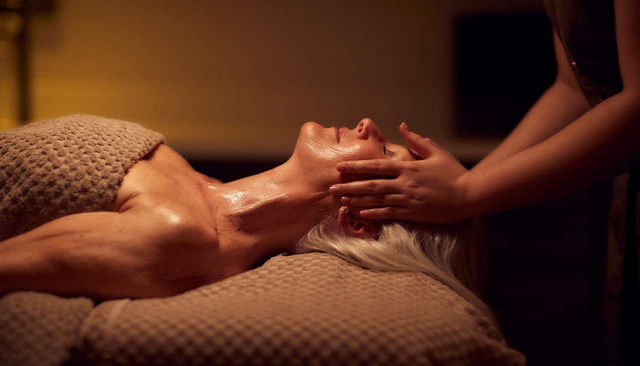 A woman recieving a face massage as part of a facial