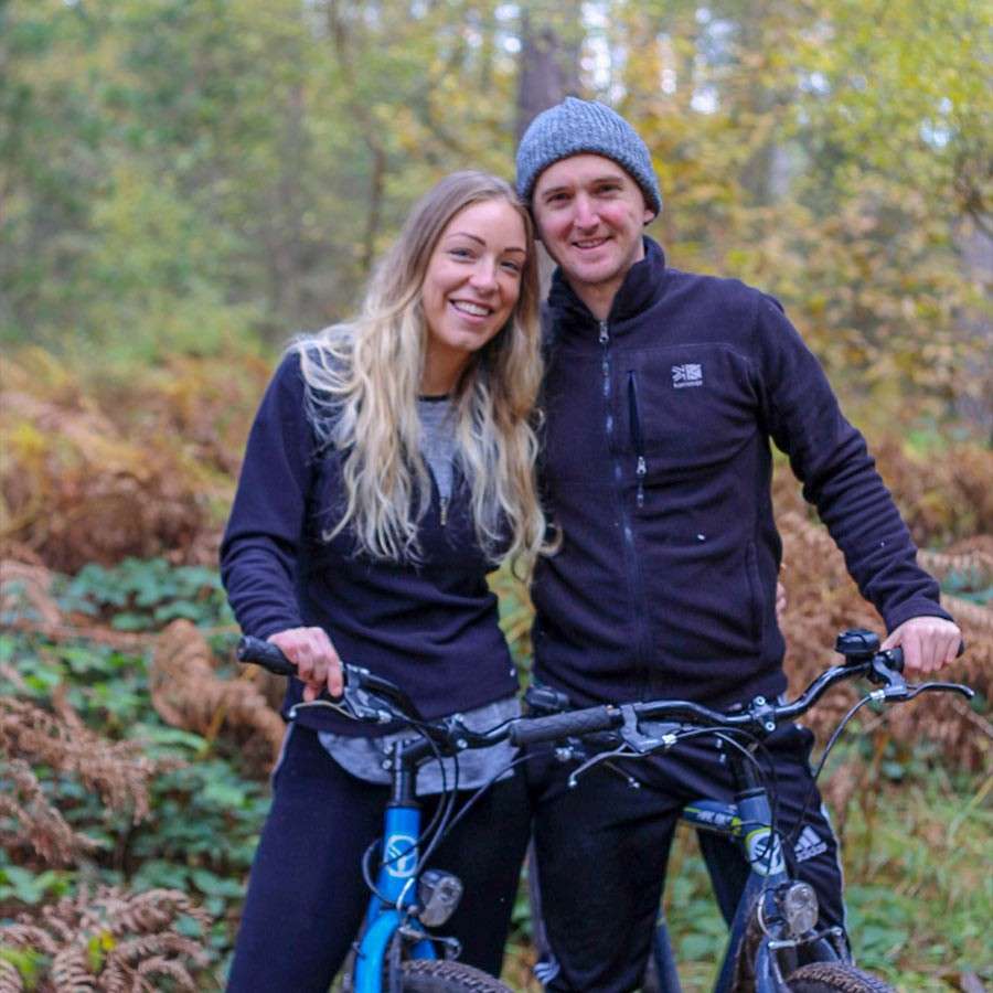 Man and woman smiling for a photo while sat on cycles