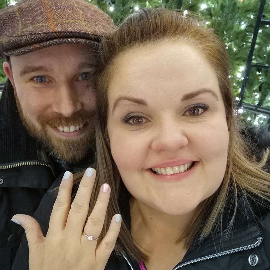 Woman showing off her engagement ring in a selfie with her partner.