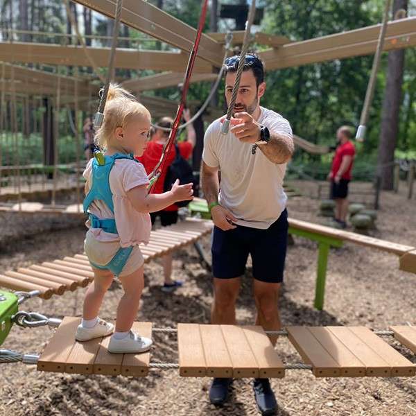 A dad helping his young daughter on the play area