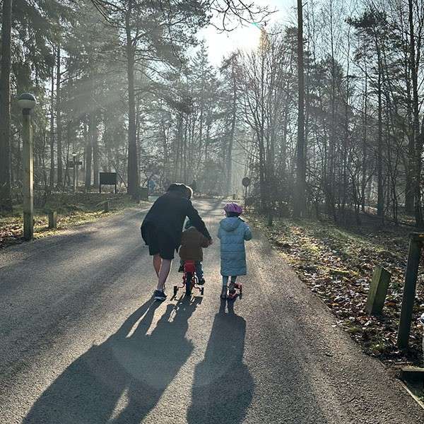 A family walking through the forest and the sun shining through the trees