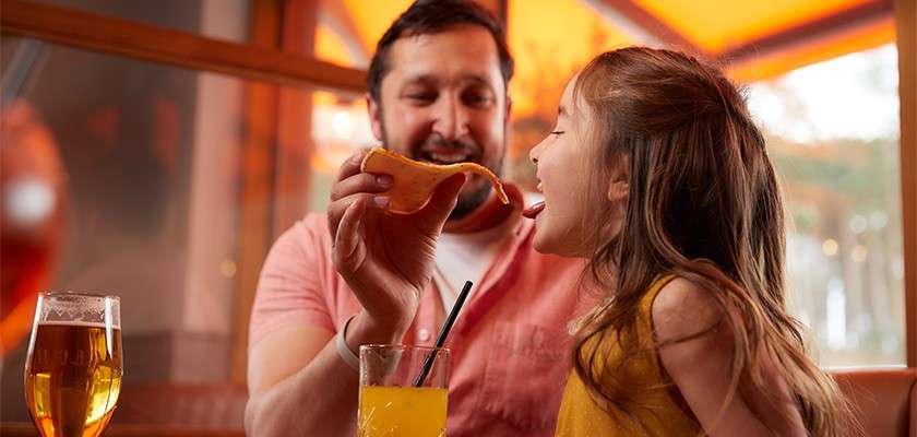 A dad feeding his daughter a pizza slice at Amalfi