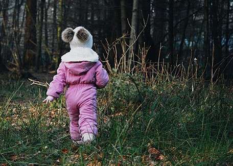 Little girl all wrapped up walking in forest  