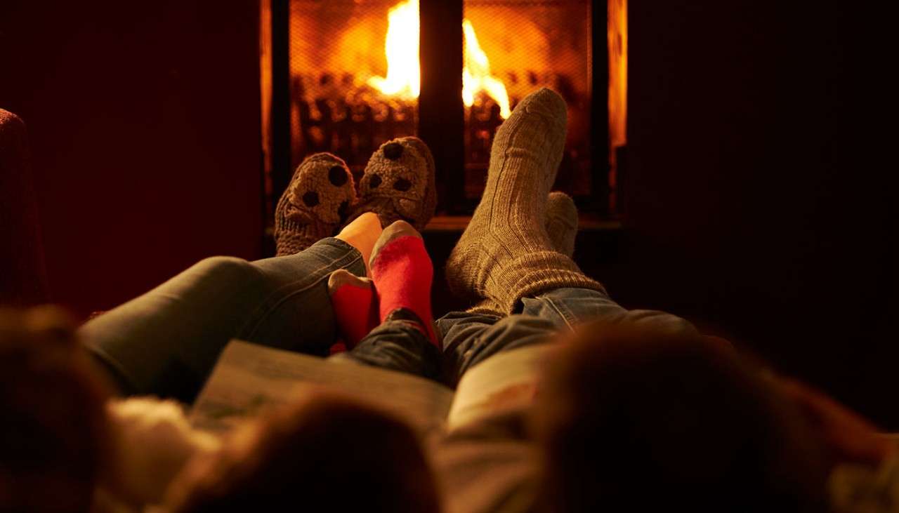 Family warming their feet up by log fire