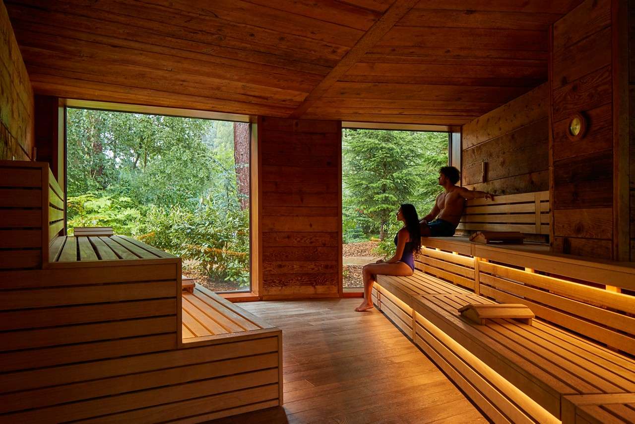 Man and woman sitting enjoying the forest views from inside the Nordic Sauna.