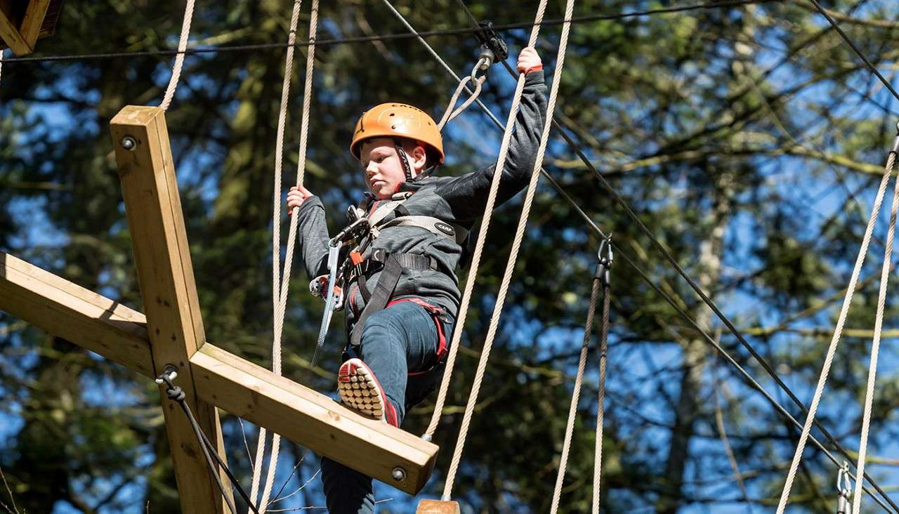 Young boy walking over a suspended bridge.