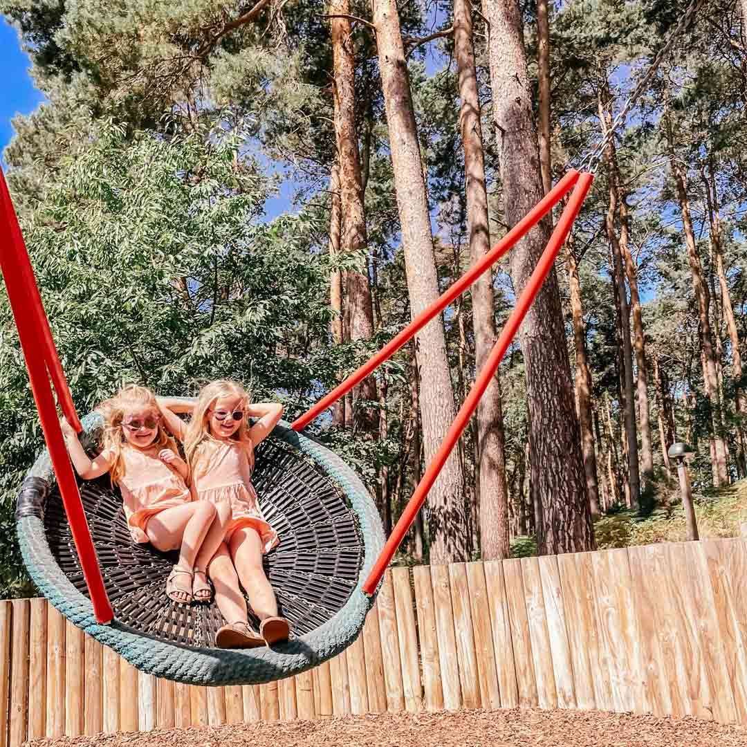 Two young girls sitting in a swing in the Play Area