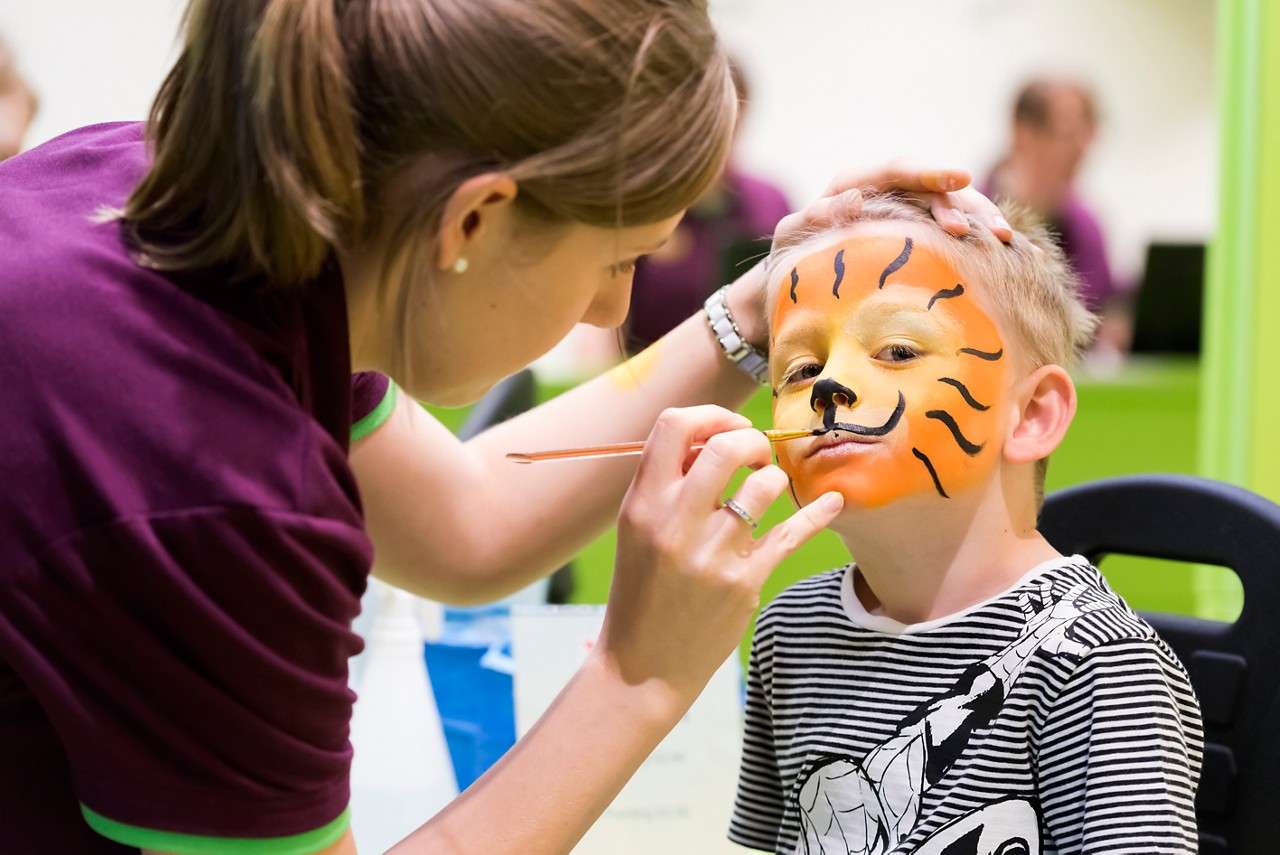 Child having their face painted by a staff member. 
