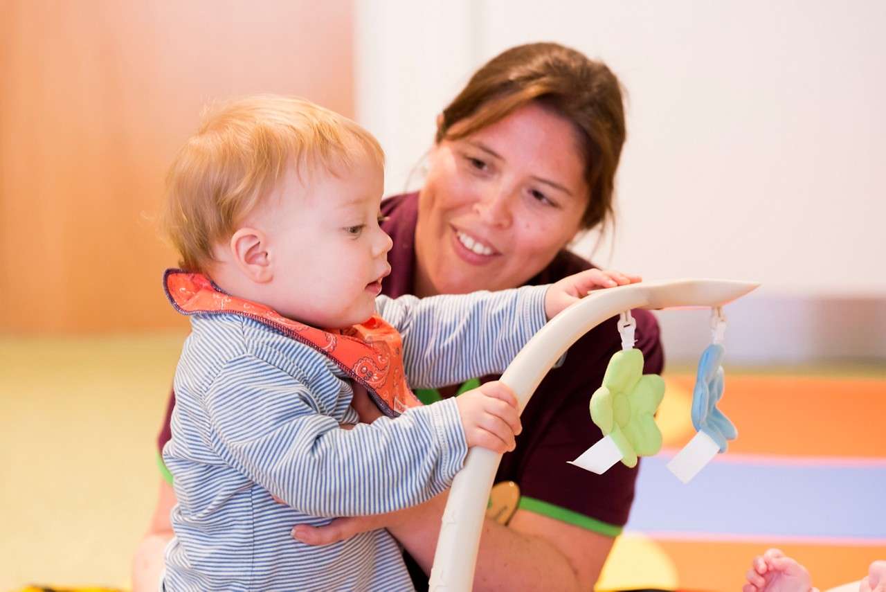 Baby practicing standing with the help of an adult.