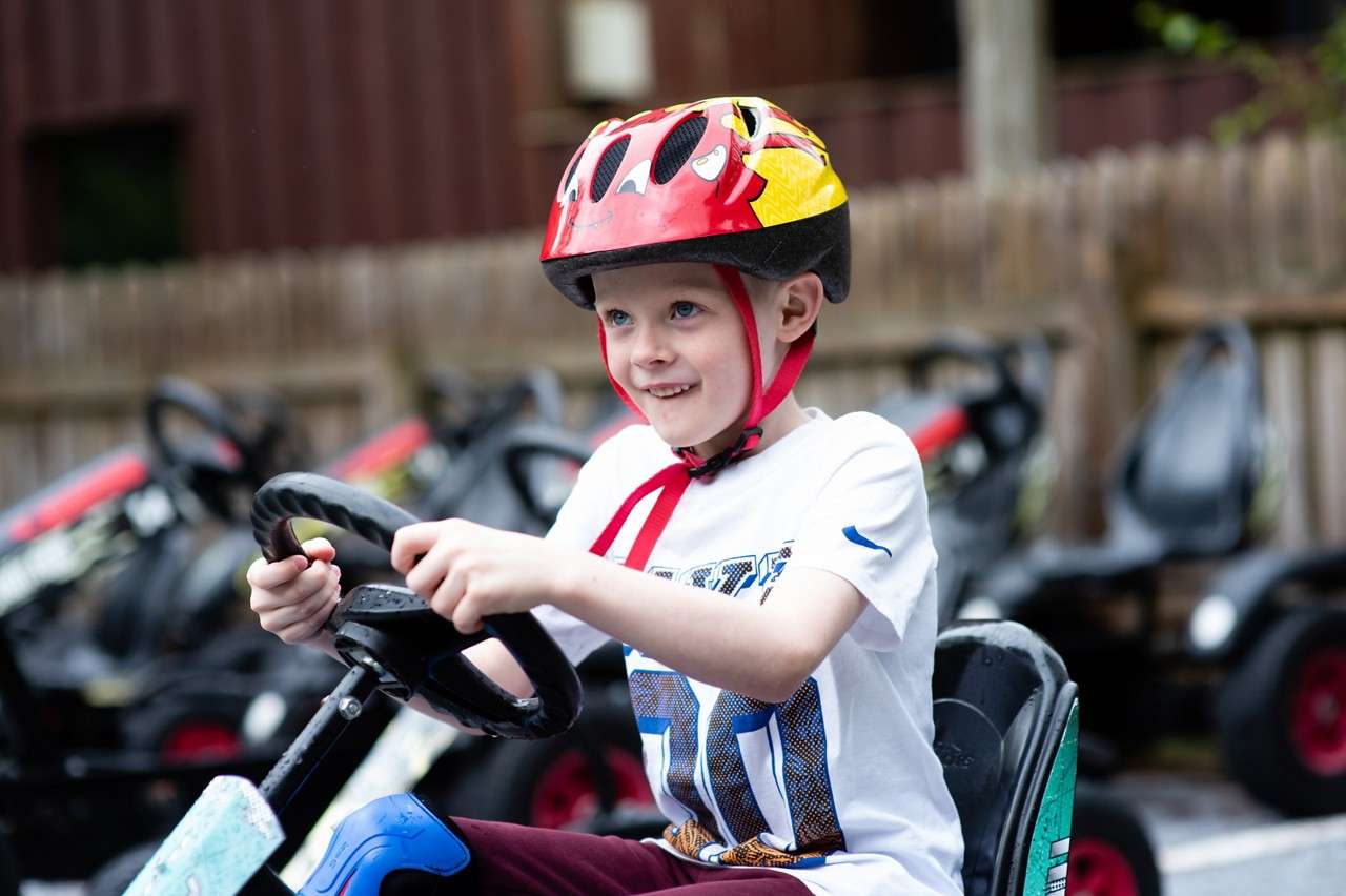 Young boy wearing a helmet whilst sitting in a go kart.