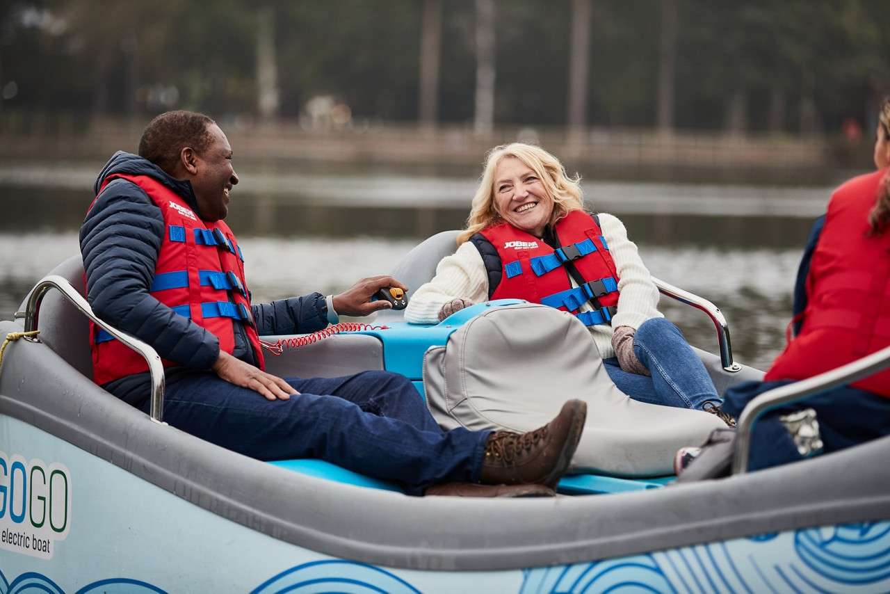 Couple relaxing in an electric boat on the lake, both are wearing life jackets.