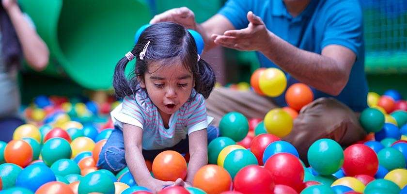 Young girl playing in a ball pit with her family