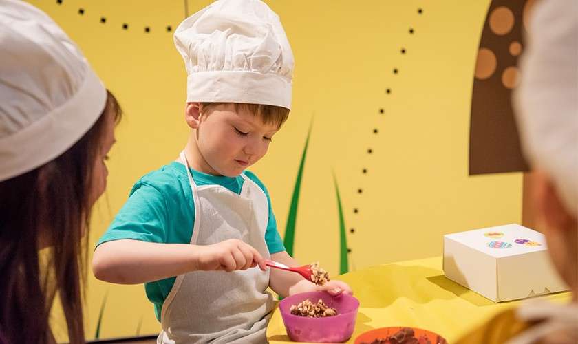 A boy making Easter chocolate treats in Easter Chocolate Chefs activity.