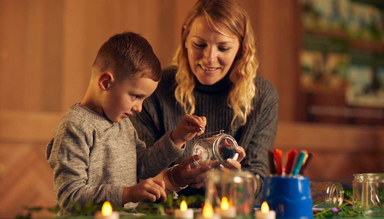 Young boy and woman decorating a glass jar.