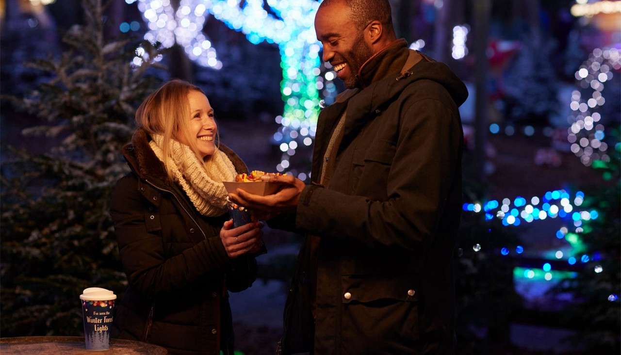 Couple standing outside in a decorated forest.