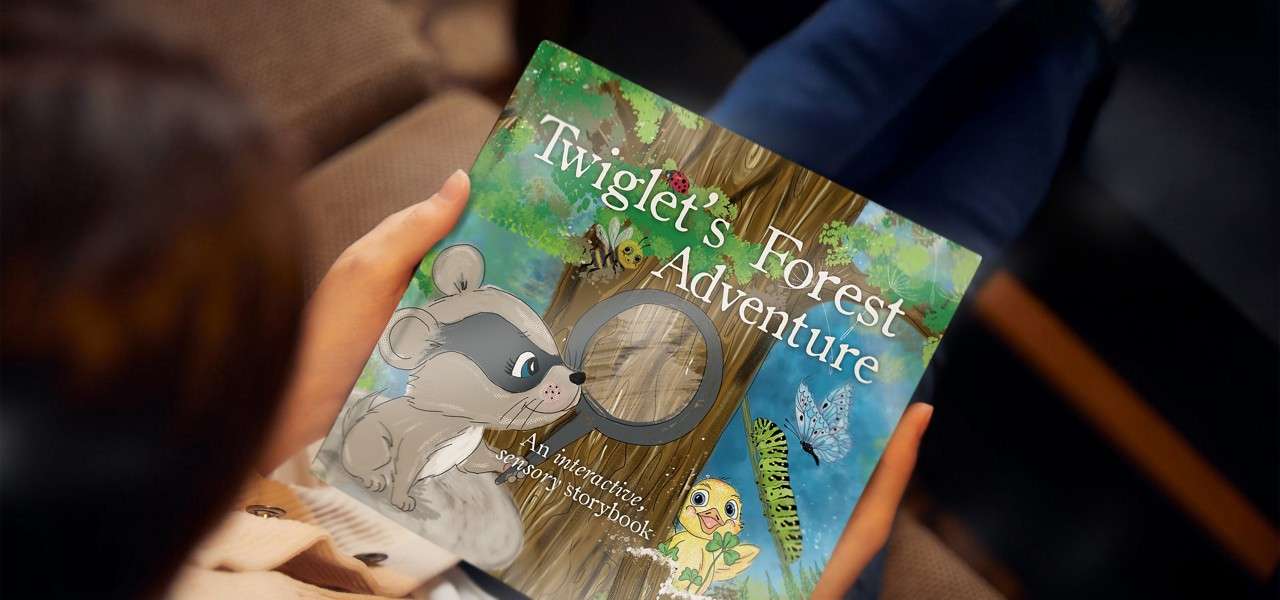 Hands hold a colorful children’s book while sitting on a couch; cover shows forest animals and a magnifying-glass cutout. Text: Twiglet's Forest Adventure. An interactive, sensory storybook.