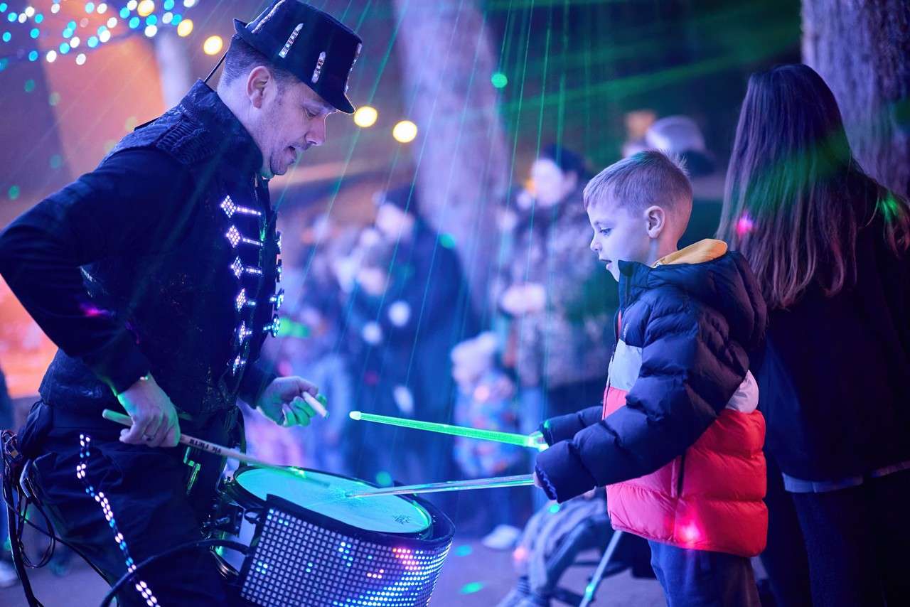 Young boy drumming with neon drumsticks.