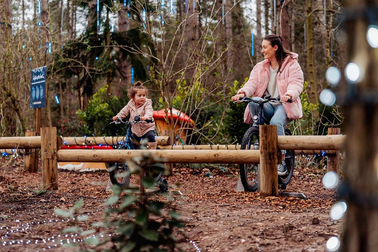 Family cycling to power lights in the forest.