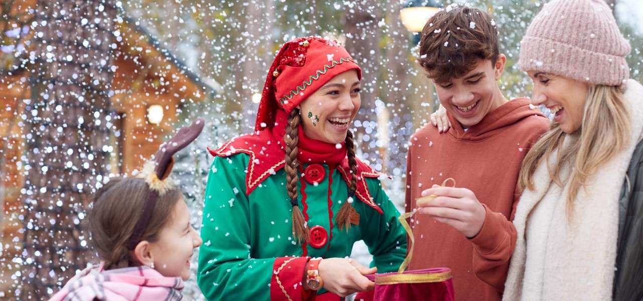 Family stood in the snow with an elf showing funny tricks.