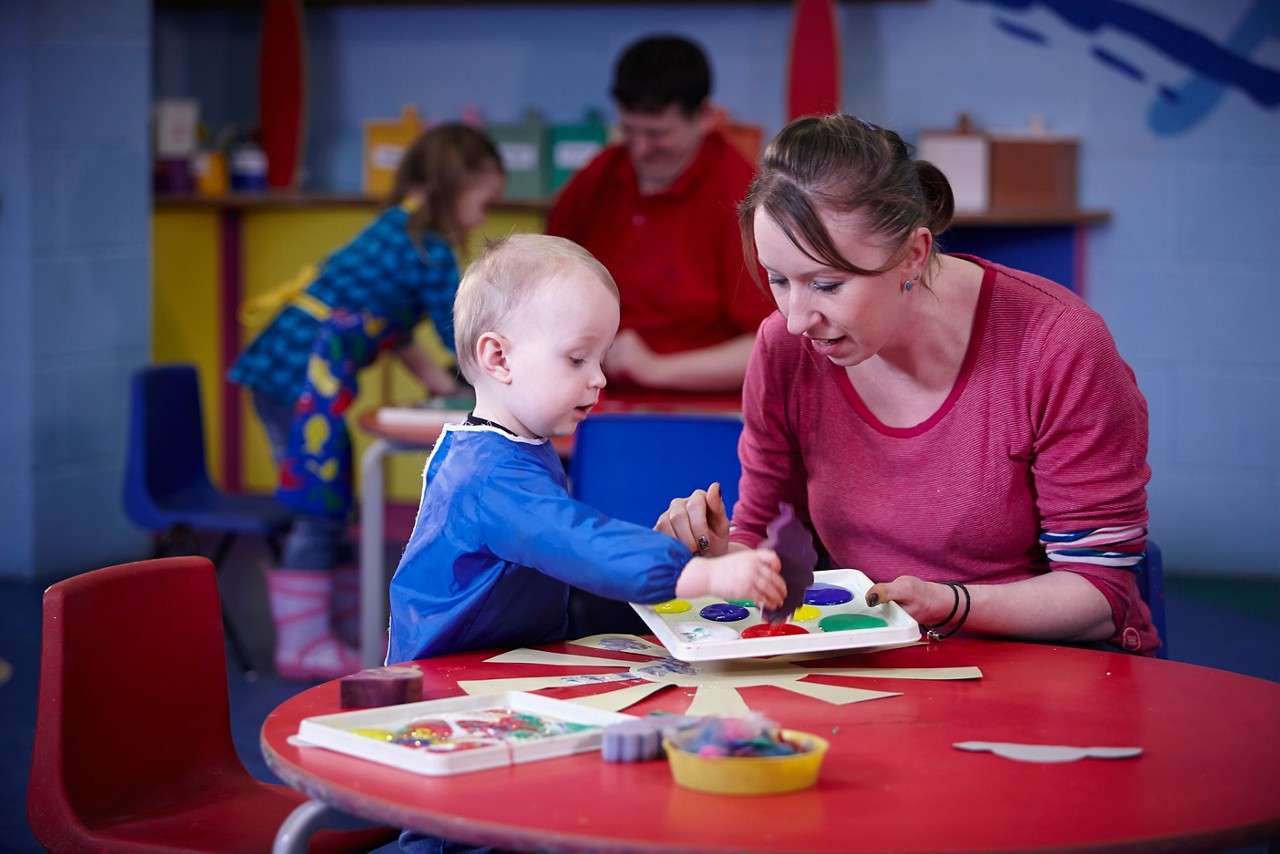 Young boy painting with an adult.