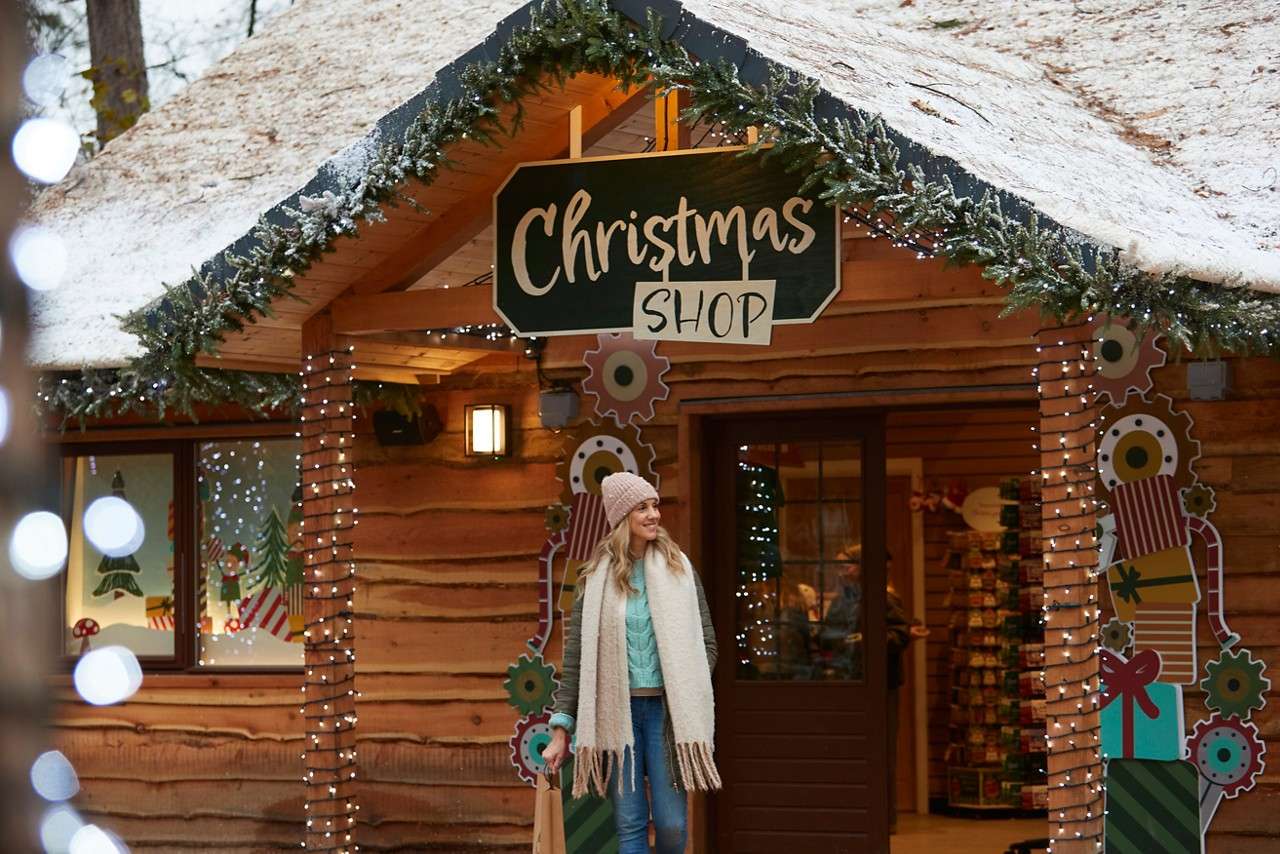 A lady stood outside the festive Christmas shop smiling.