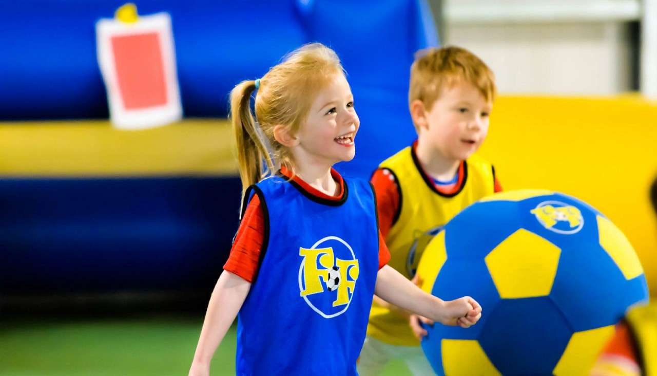 Two toddlers playing with a large inflatable football