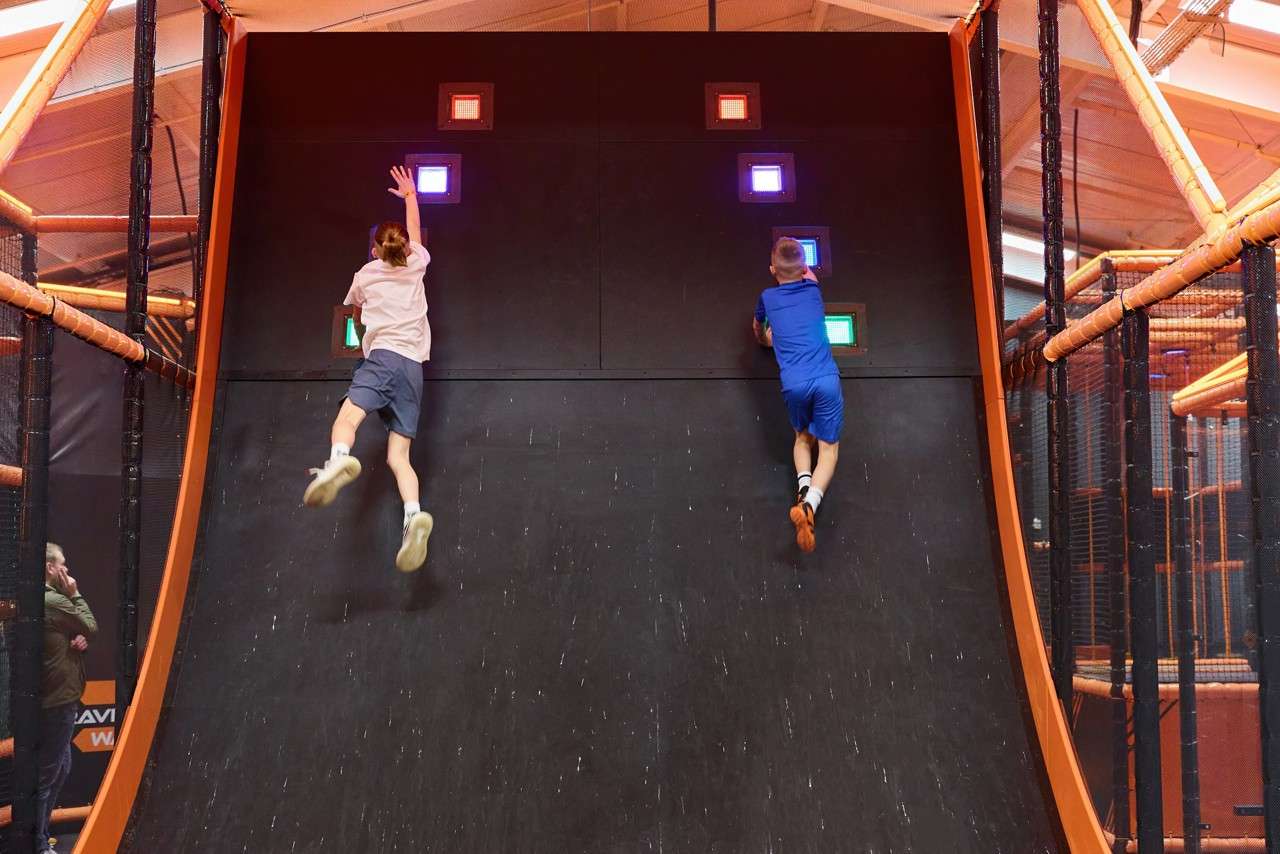 Two young people jumping to reach glowing lights.