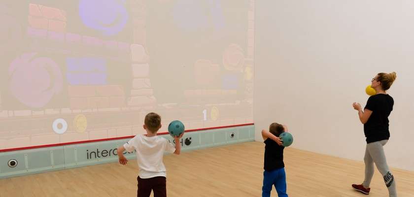 Family throwing balls at an interactive wall