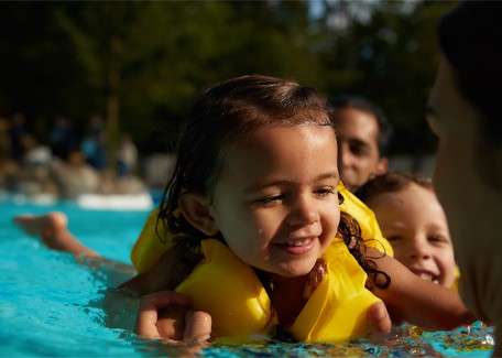 A little girl smiling in the Subtropical Swimming Paradise wearing a bouyancy aid.