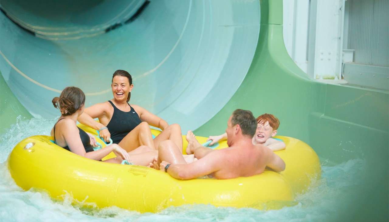 Family in a large inflatable going down a large tube slide.