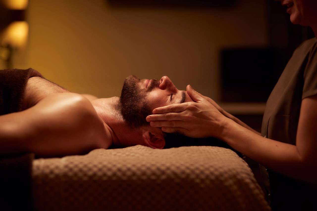 Spa therapist giving a man a relaxing facial treatment.