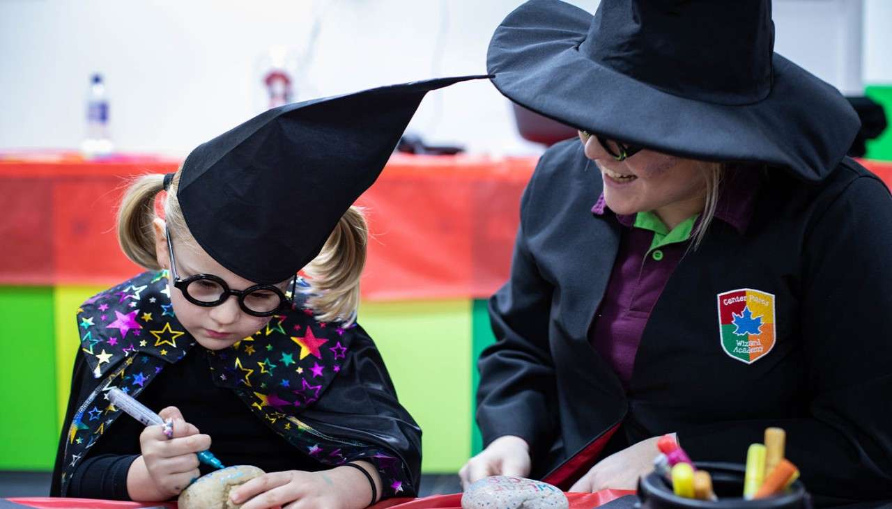 A child and instructor dressed as wizards as part of the Wizard Academy activity 