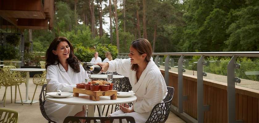 Women in robes enjoying a meal on the balcony of the spa