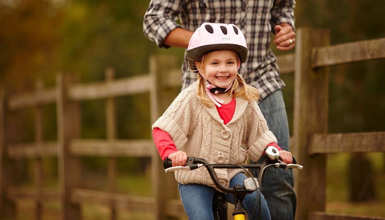 A little girl cycling on a path through the forest 