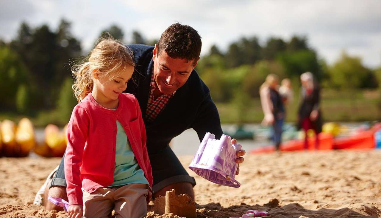 A father helping his daughter build a sandcastle on the beach