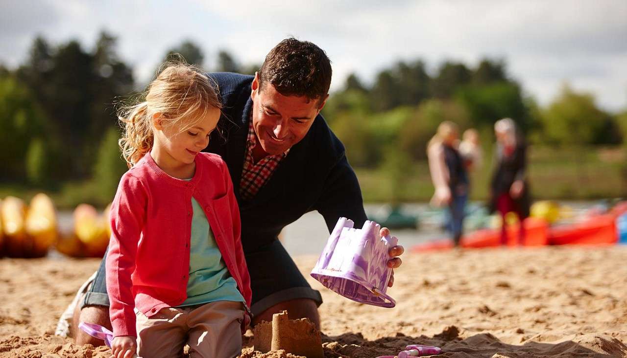 A father helping his daughter build a sandcastle on the beach