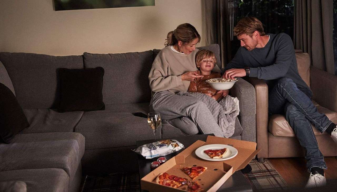 A family eating pizza on the sofa in their lodge 