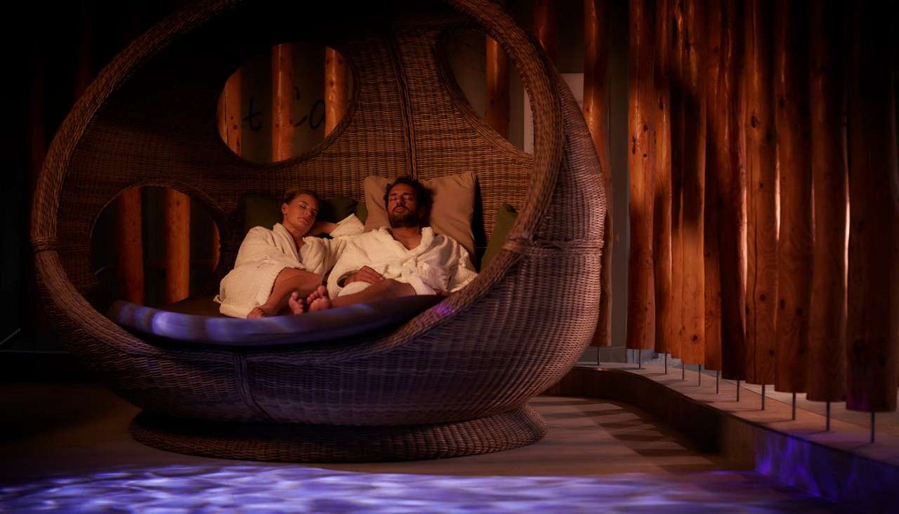 Couple sitting in a large seat in the Forest Nesting room.