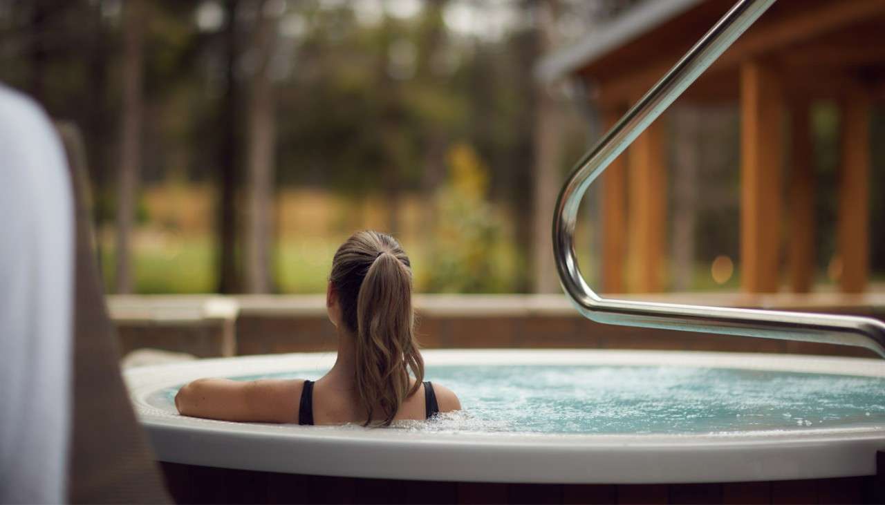 Woman leaning on the edge of a bubbling outdoor hot tub
