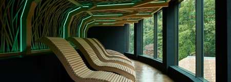 Wooden contoured seating underneath a decorative ceiling pattern.