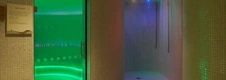 Rainfall showers lit with LED lighting behind a glass door.