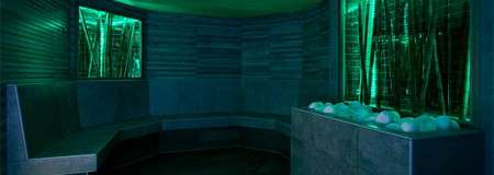 Glowing salt steam room lined with geometric benches and a basin full of round stones.