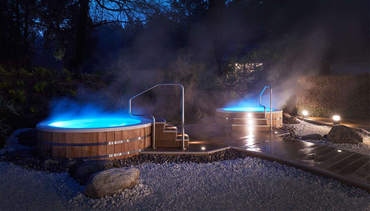 Two outdoor hot tubs with steam in the dark 