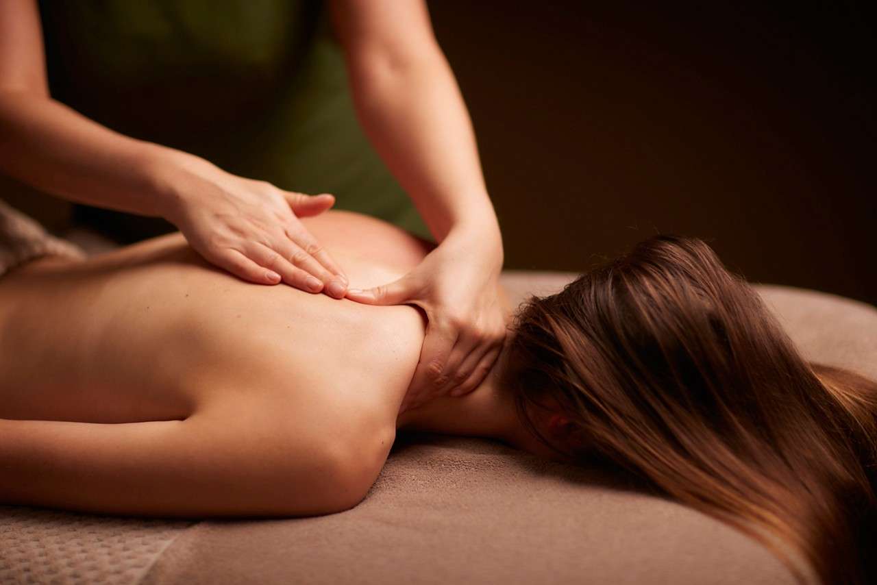 Spa therapist giving a woman a relaxing back massage body treatment.