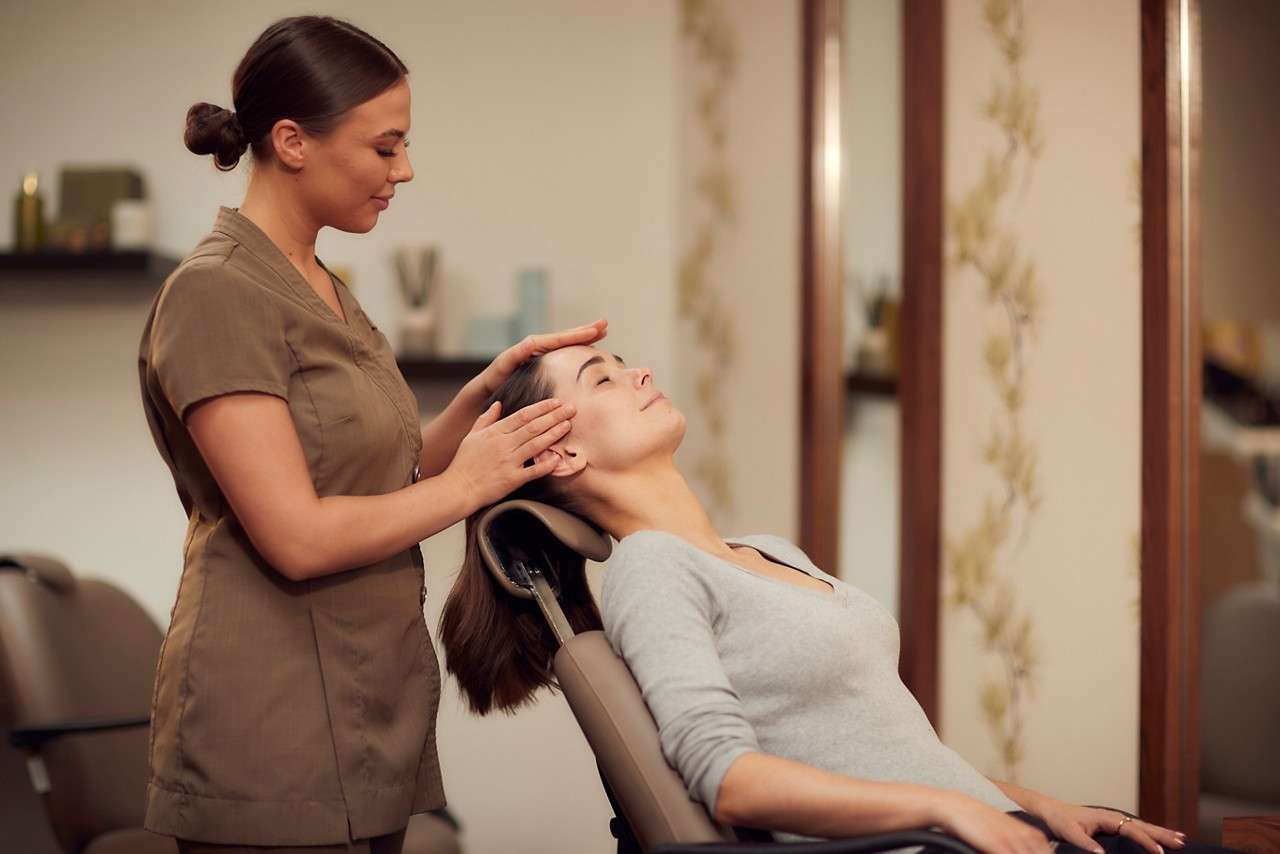 Spa therapist giving a woman a relaxing head massage in the express treatment area.