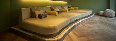 Curved green lounging area with throw cushions.