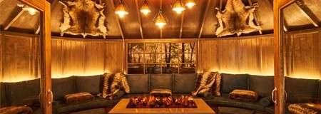 Inside a cosy Scandinavian Snug with hanging lighting, blankets and throw cushions.