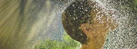 Woman's head being sprayed with water from a multi-sensory shower.
