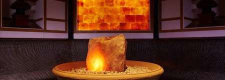 Ceramic dish with small stones surrounding a large piece of salt rock.
