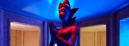 Colourful Balinese statue in a room with multiple entrances.
